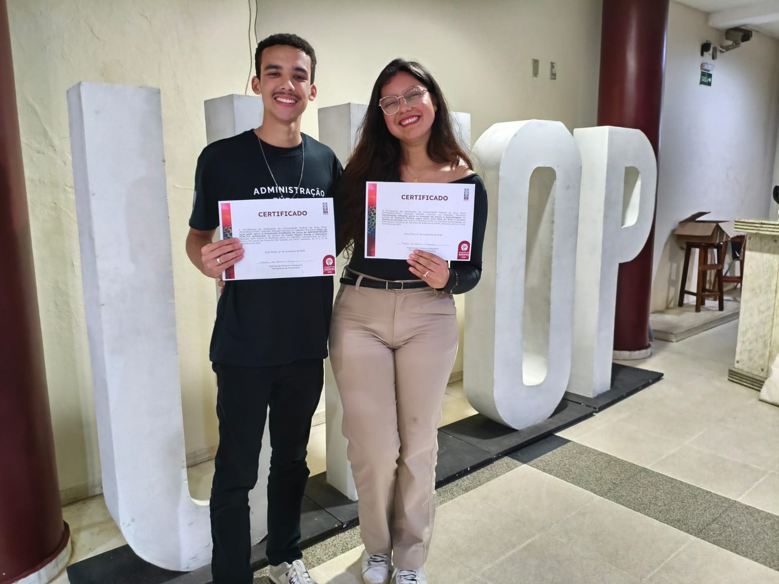 Foto dos discentes Carlos Miguel e Thamyris Rafaele segurando os certificados das premiações